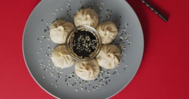 Tabağın kompozisyonu, Dim Sum mantı ve soya soslu çubuklarla kırmızı arka plan. Yiyecek, içecek ve renk konsepti.