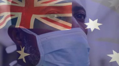 Avustralya bayrağının şehir caddesinde maskeli Afro-Amerikan bir adamın üzerinde dalgalanması. covid 19 salgın konsepti boyunca dijital olarak üretilen küresel sağlık önlemleri.