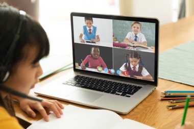 Görüntülü konuşma için dizüstü bilgisayar kullanan Asyalı bir kız. Ekranda çeşitli ilkokul öğrencileri gülümsüyor. iletişim teknolojisi ve çevrimiçi eğitim, dijital kompozit resim.