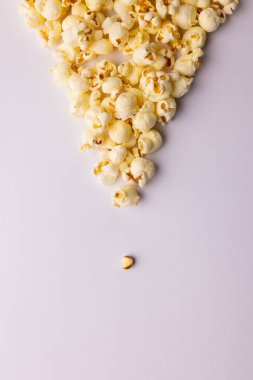 Beyaz arka planda patlamış mısırın dikey görüntüsü. Yiyecek, atıştırmalık, sinema ve Amerikan mutfağı konsepti.