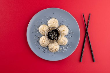 Asya hamur köfteleri, soya sosu ve kırmızı arka planda yemek çubukları. Asyalı lezzetli ev yemekleri ve sağlıklı yiyecekler..