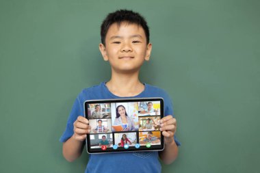 Çeşitli ilkokul öğrencileriyle video görüşmesi için elinde tablet olan gülümseyen Asyalı çocuk. iletişim teknolojisi ve çevrimiçi eğitim, dijital kompozit resim.