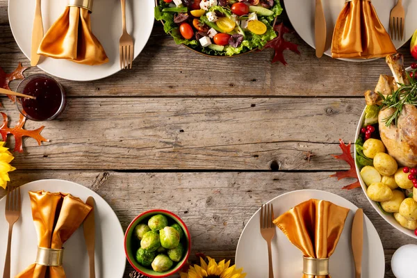 Thanksgiving table with roast turkey, vegetables and autumn decoration with copy space on wood. Thanksgiving, autumn, fall, american tradition and celebration concept.