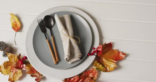 有餐具的盘子和白色表面的树叶的秋天装饰的视频 感恩节 美国文化 传统和庆祝视频 — 图库视频影像