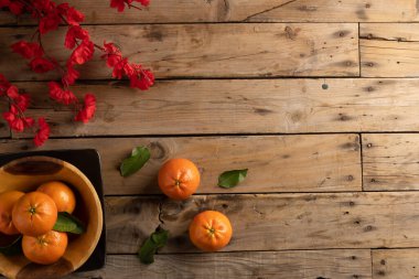 Ahşap arka planda kırmızı çiçekler ve portakalların bileşimi. Çin yeni yılı, gelenek ve kutlama konsepti.