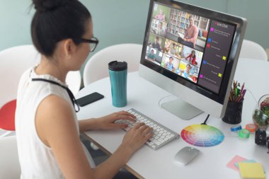 Asyalı bir kadın ekranda çeşitli ilkokul öğrencilerinin gülümsemesiyle video görüşmesi için bilgisayar kullanıyor. iletişim teknolojisi ve çevrimiçi eğitim, dijital kompozit resim.