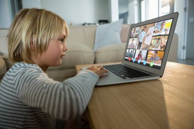 Beyaz çocuk ekranda çeşitli ilköğretim öğrencileri gülümserken görüntülü konuşma için laptop kullanıyor. iletişim teknolojisi ve çevrimiçi eğitim, dijital kompozit resim.