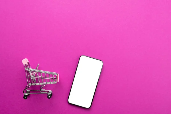 Zusammensetzung Von Warenkorb Und Smartphone Mit Kopierraum Auf Rosa Hintergrund — Stockfoto