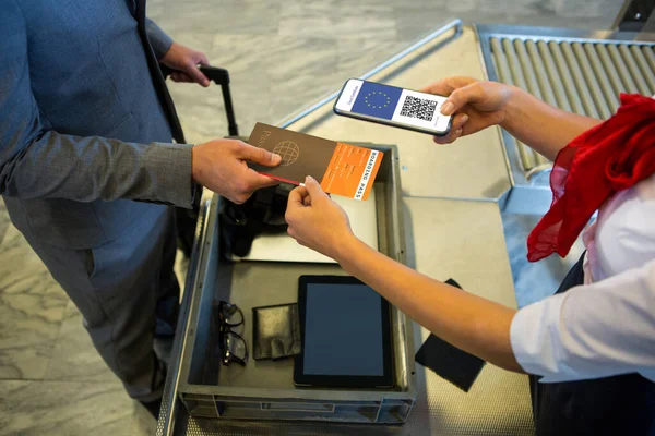 Man at airport showing documents and smartphone with covid 19 vaccine passport at check in. global covid 19 pandemic concept digitally generated video.