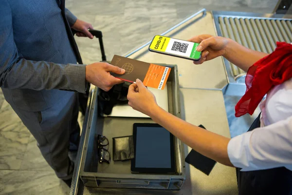 Man at airport showing documents and smartphone with covid 19 vaccine passport at check in. global covid 19 pandemic concept digitally generated video.