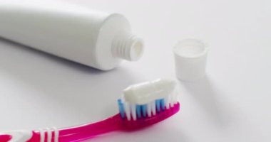 Beyaz arka planda diş fırçası ve yapıştırıcının yakın çekim videosu. Sağlık, stomatoloji ve kopyalama alanı kavramı.