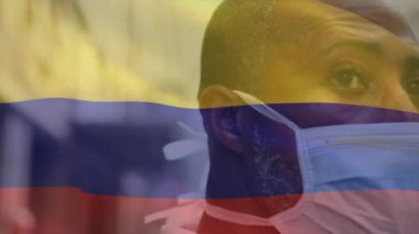 Kamerun bayrağının şehir caddesinde maskeli Afro-Amerikan bir adamın üzerinde dalgalanmasının animasyonu. covid 19 salgın konsepti boyunca dijital olarak üretilen küresel sağlık önlemleri.