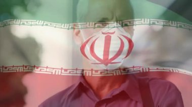 İranlı bayrağın şehir caddesinde yüz maskesi takan beyaz adamın üzerinde dalgalanması. covid 19 salgın konsepti boyunca dijital olarak üretilen küresel sağlık önlemleri.