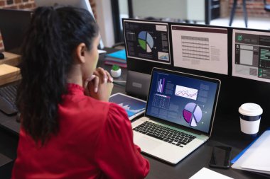Çift ırklı iş kadını, ekranda grafik ve istatistiksel verilerle masada oturuyor. iş iletişimi ve dijital arayüz teknolojisi dijital kompozit görüntü.