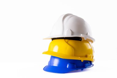 Beyaz yüzeyde duran kask yığını görüntüsü. Çalışma, koruma, güvenlik ve yapı ekipmanları kavramı.