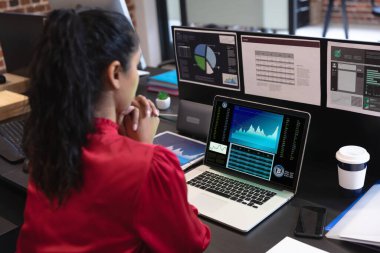 Çift ırklı iş kadını masada oturuyor, ekranda istatistiksel verileri olan bir dizüstü bilgisayar kullanıyor. iş iletişimi ve dijital arayüz teknolojisi dijital kompozit görüntü.