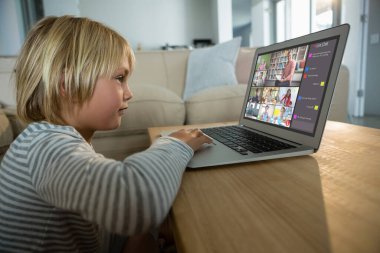 Beyaz çocuk ekranda çeşitli ilköğretim öğrencileri gülümserken görüntülü konuşma için laptop kullanıyor. iletişim teknolojisi ve çevrimiçi eğitim, dijital kompozit resim.