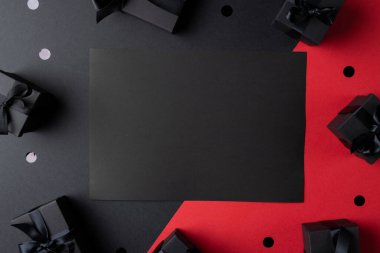 Hediyelerin kompozisyonu ve üzerinde gri ve pembe arkaplan olan siyah kart. Perakende, alışveriş ve Kara Cuma konsepti.