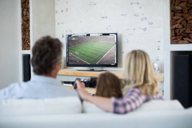 Beyaz bir aile televizyonda futbol maçı seyrediyor. Küresel spor kavramı, dijital kompozit görüntü.