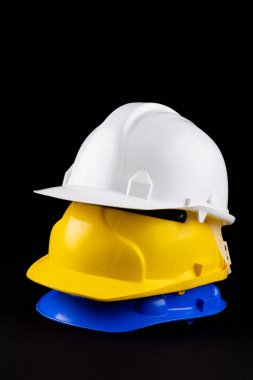 Siyah yüzeyde duran kaskların dikey görüntüsü. Çalışma, koruma, güvenlik ve yapı ekipmanları kavramı.