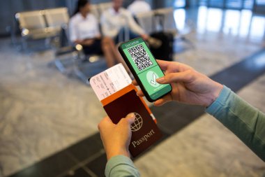 Havaalanında elinde belgeler ve elinde 19 aşılı pasaportlu akıllı telefon olan bir kadın var. küresel covid 19 salgın konsepti dijital olarak oluşturulmuş video.