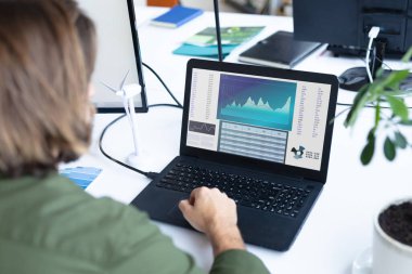 Masada oturan beyaz iş kadını ekranda istatistiksel verileri olan bir dizüstü bilgisayar kullanıyor. iş iletişimi ve dijital arayüz teknolojisi dijital kompozit görüntü.