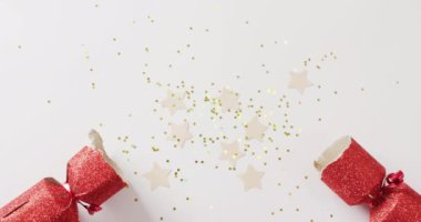 Kırmızı noel krakeri, yıldızlar ve dekorasyonun beyaz arka planda fotokopi alanı olan videosu. Noel, gelenek ve kutlama konsepti.