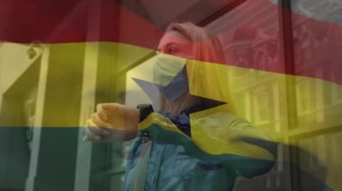 Caddede yüzü maskeli beyaz bir kadının üzerinde sallanan Gana bayrağının animasyonu. covid 19 salgın konsepti boyunca dijital olarak üretilen küresel sağlık önlemleri.