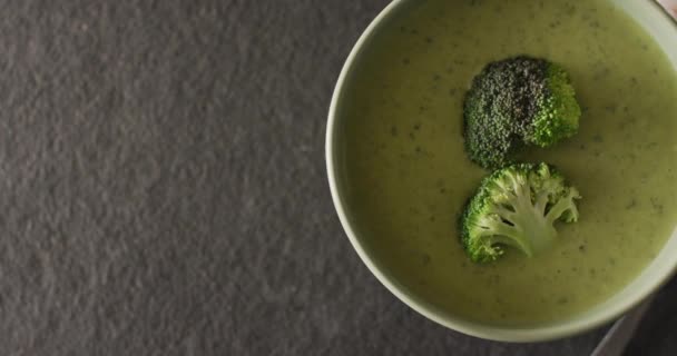 スプーンとスパイスとグレーのテーブルの上にボウルにクリームブロッコリースープのビデオ アメリカ料理 食べ物 料理の概念 — ストック動画