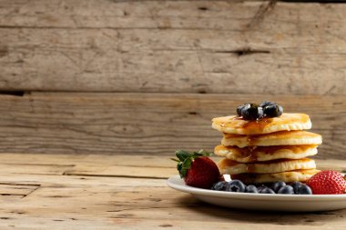 Yaban mersinli ve akçaağaç şuruplu krep yığınının yatay görüntüsü. Lezzetli ev yapımı yemekler, organik malzemeler ve sağlıklı yiyecekler..