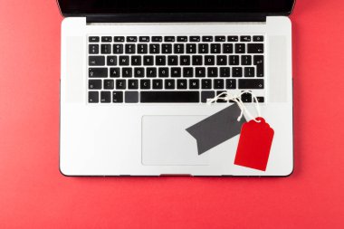 Pembe arka planda dizüstü bilgisayar ve hediye etiketleri var. Perakende, alışveriş ve Kara Cuma konsepti.