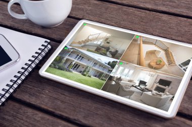 Tablet, ahşap masada duran güvenlik kameralarından eve bakıyor. güvenlik, güvenlik, izleme ve dijital arayüz.