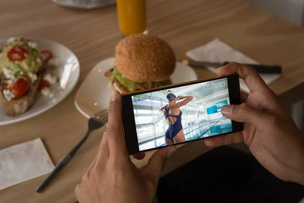 Händerna Afrikansk Amerikansk Man Restaurang Titta Kvinnliga Simmare Smartphone Sport — Stockfoto