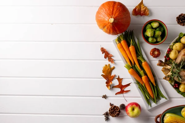 Overhead view of thanksgiving table with roast turkey, vegetables autumn decoration and copy space. Thanksgiving, autumn, fall, american tradition and celebration concept.