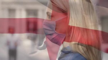 Şehir caddesinde yüz maskesi takan beyaz bir kadının üzerinde bayrak sallama animasyonu. covid 19 salgın konsepti boyunca dijital olarak üretilen küresel sağlık önlemleri.