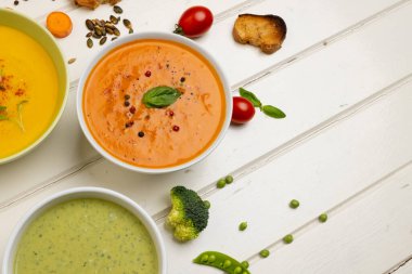 Beyaz ahşap üzerinde havuç, brokoli ve domates çorbasının fotokopi alanındaki yatay görüntüsü. Lezzetli ev yemekleri ve sağlıklı yemekler..