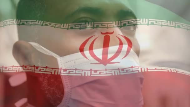 Animación Bandera Irán Ondeando Sobre Hombre Afroamericano Con Máscara Facial — Vídeo de stock