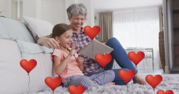 Animação Balões Cardíacos Sobre Avó Caucasiana Feliz Neta Usando Tablet — Vídeo de Stock