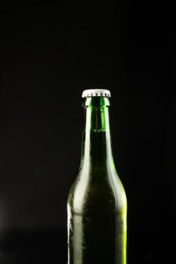 Beyaz kapaklı yeşil cam bira şişesi resmi, siyah arka planda kopyalama alanı var. Alkol, içecek ve bira günü kutlamaları..