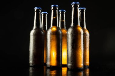 Siyah arka planda kopyalama alanı olan mavi kapaklı altı bira şişesi resmi. Alkol, içecek ve bira günü kutlamaları..