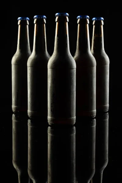 Вертикальное Изображение Пяти Тёмных Стеклянных Бутылок Пива Голубыми Колпачками Чёрном — стоковое фото