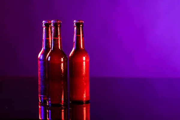 三瓶带皇冠的棕色啤酒瓶的图像 背景为紫色 茶点和长假庆祝概念 — 图库照片