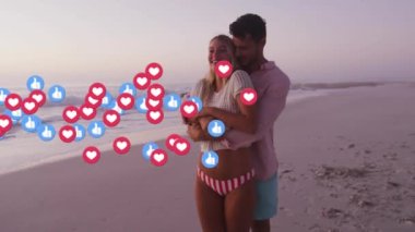 Sahilde yürüyen beyaz bir çiftin üzerine düşen sosyal medya simgeleri. Küresel sosyal medya kavramı dijital oluşturulmuş video.