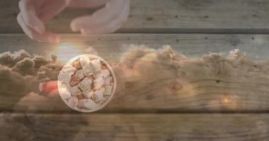 Ellerinin üzerinde bulutlar, tahta arka planda kakaolu kupayı tutarken gökyüzünün animasyonu. Sonbahar geleneği ve dijital olarak üretilen video konsepti.