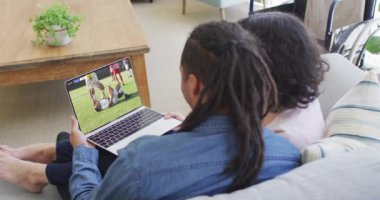 İki Afrikalı Amerikalının kanepede oturup dizüstü bilgisayardan futbol maçı izlediği bir video. Futbol ve tezahürat kavramı.
