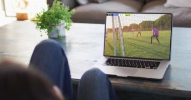 Kanepede oturup dizüstü bilgisayardan futbol maçı izleyen birinin videosu. Futbol ve tezahürat kavramı.