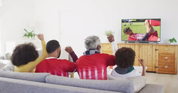 アフリカ系アメリカ人の家庭では 多様な男性サッカー選手がスクリーンで試合をしてテレビを見ている グローバルスポーツの概念 デジタル複合ビデオ — ストック動画