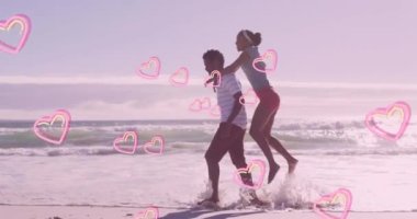 Mutlu Afrika kökenli Amerikalı çiftin kumsalda sevişmesi üzerine pembe kalplerin animasyonu. Aşk, birliktelik, romantizm ve tatil konsepti dijital olarak oluşturulmuş video.