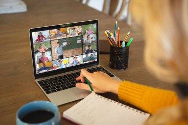 Beyaz bir kadın ekranda çeşitli ilkokul öğrencilerinin gülümsediği bir video görüşmesi için dizüstü bilgisayar kullanıyor. iletişim teknolojisi ve çevrimiçi eğitim, dijital kompozit resim.