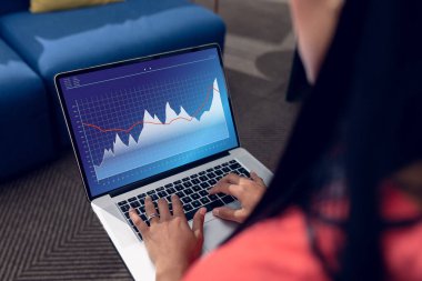 Çift ırklı iş kadını ekranda grafikleri olan bir laptop kullanıyor. İş iletişimi, esnek çalışma, veri, kapsayıcılık ve dijital arayüz kavramı.